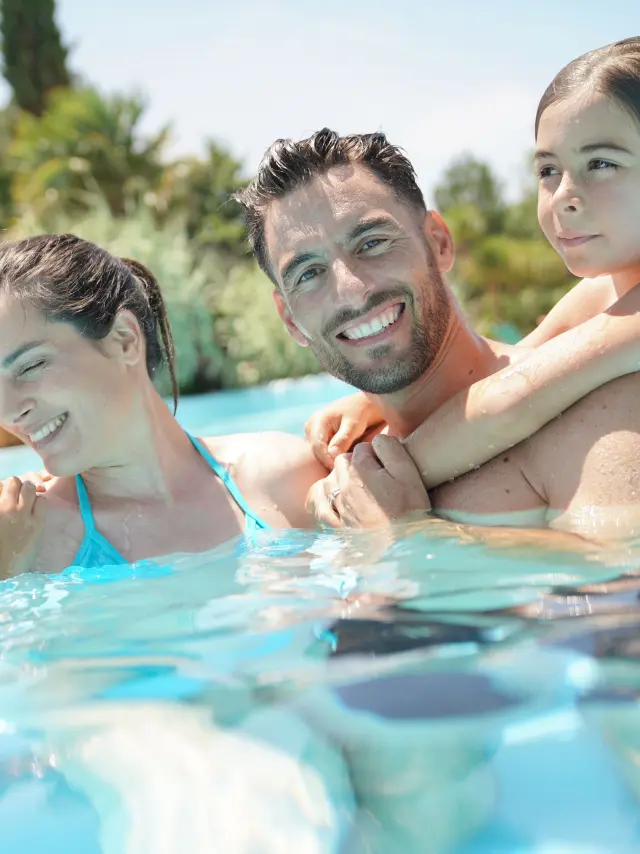 Portrait of happy family at the swimming-pool in summer