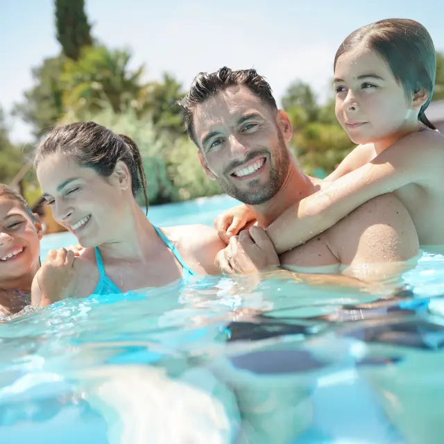 Portrait of happy family at the swimming-pool in summer