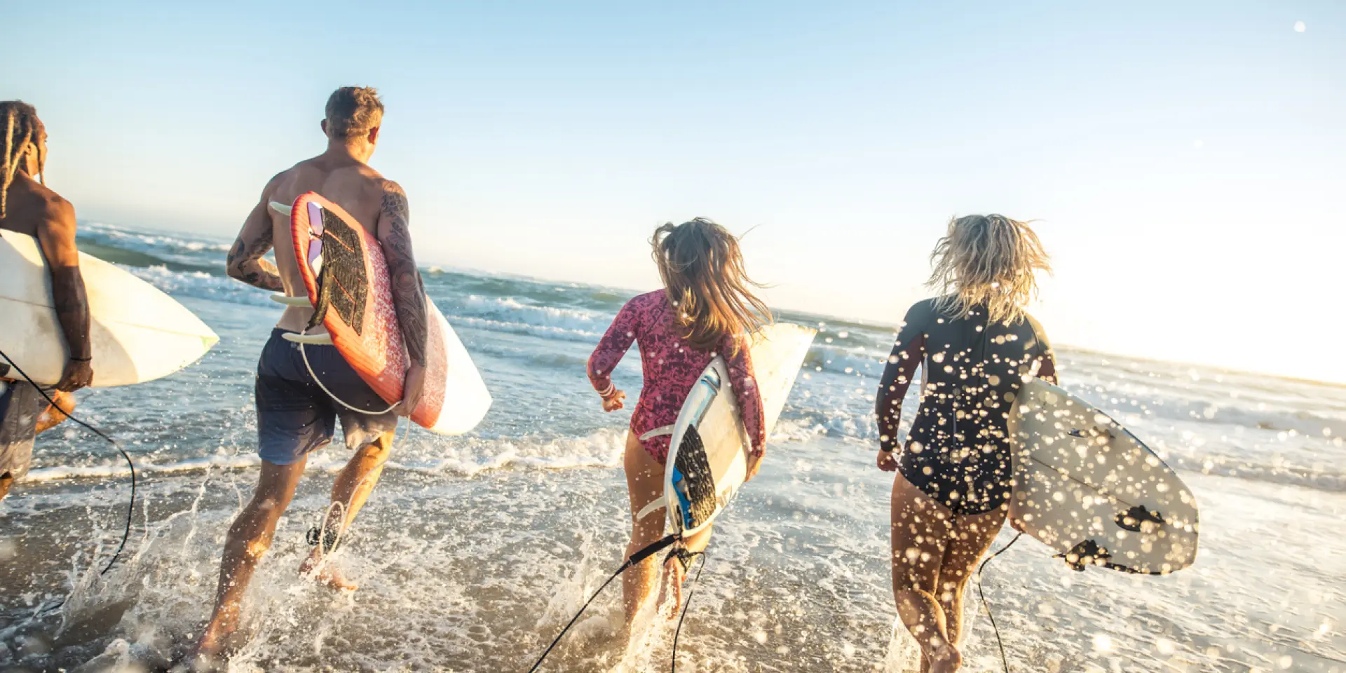 Freunde, die mit ihren Surfbrettern ins Meer laufen