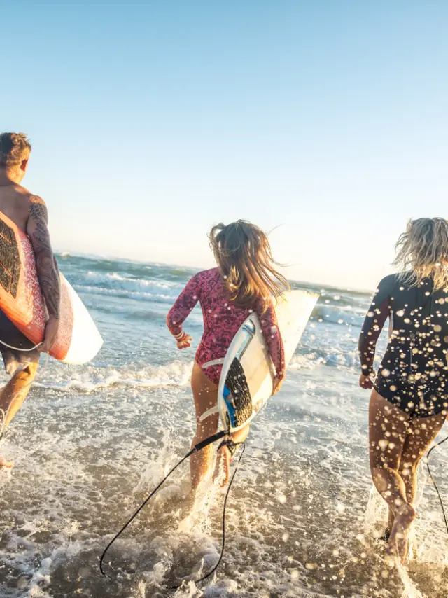 Friends running into the sea with surfboards