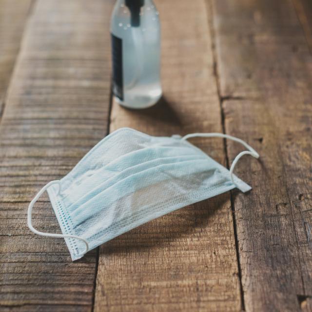Un masque chirurgical et un distributeur de gel hydroalcoolique sur un plancher.