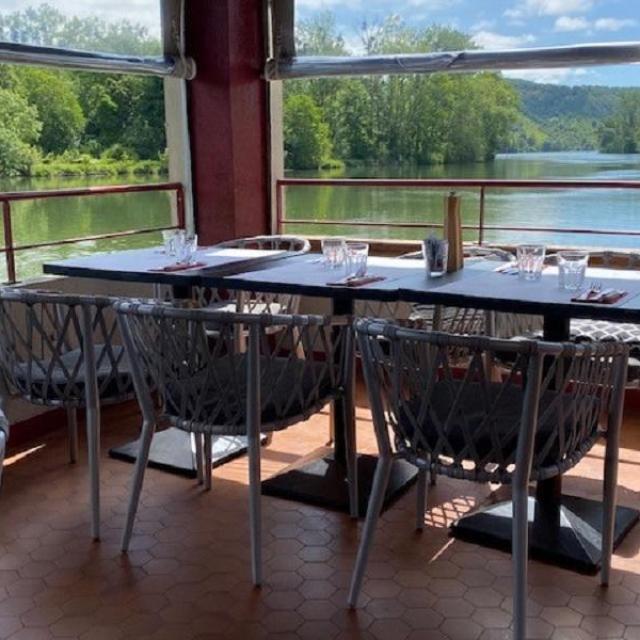 Salle de restaurant au bord de seine avec vue sur la seine et des arbres par temps ensoleillé