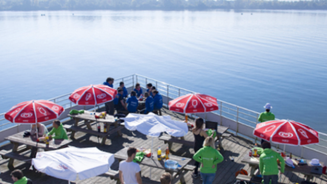 Terrasse en bois sur laquelle se restaurent des gens au bord du lac de la base des loisirs de Léry-Poses en Normandie