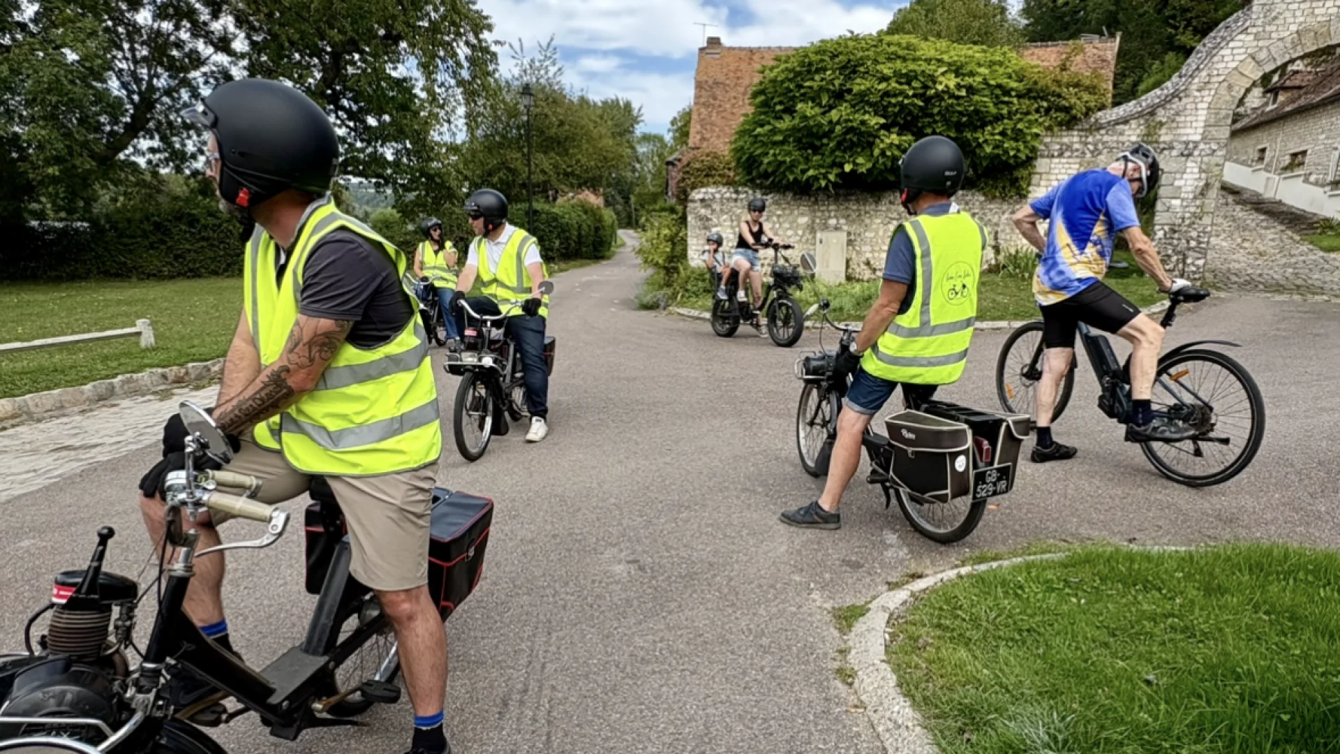 Groupe de participants en Solex traversant un village normand