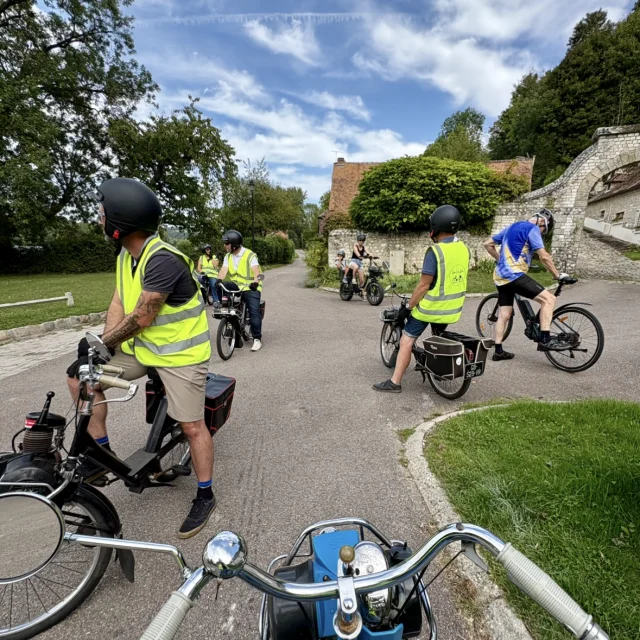Groupe de participants en Solex traversant un village normand