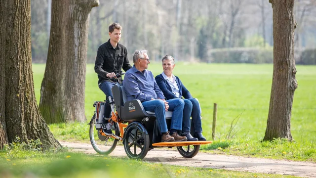 Deux personnes en situation de handicap sont en balade dans en pleine nature à bord d'un vélo adapté. Il s'agit d'un vélo 