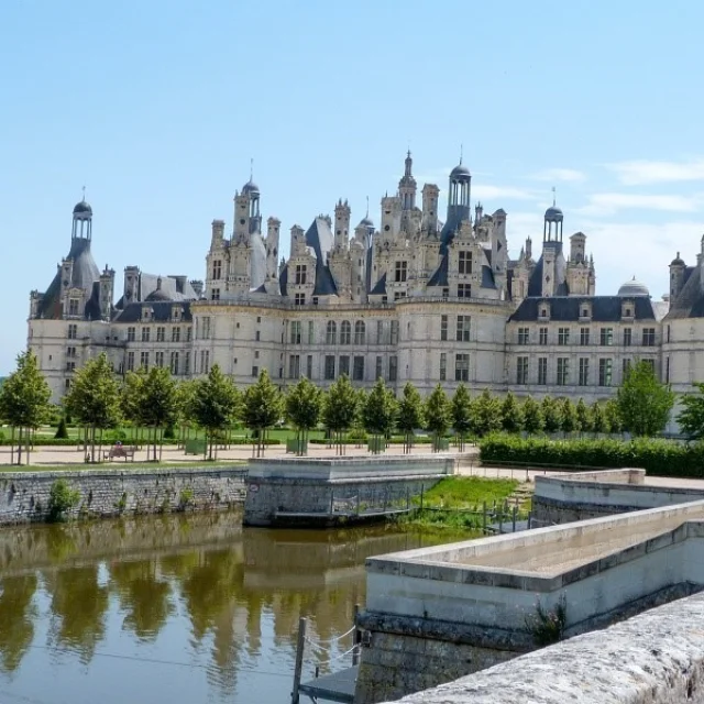 Vue du Château de Chambord, chef-d'œuvre de la Renaissance française, avec ses tours et tourelles majestueuses se reflétant dans le canal