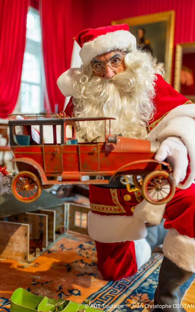 Père Noël présentant un jouet ancien dans une salle décorée pour Noël au Château Royal d’Amboise.