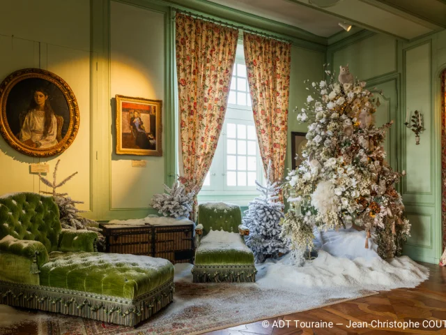 Salon décoré de Noël au château de Villandry, avec un sapin enneigé et un mobilier ancien vert.