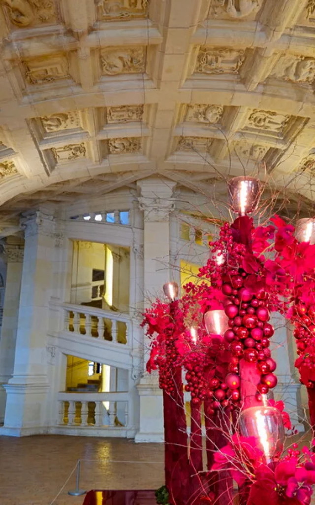 Décorations de Noël rouges installées au pied de l’escalier à double révolution du château de Chambord.