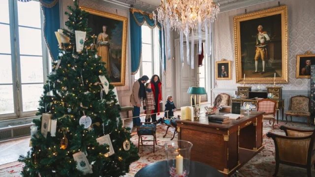 Famille visitant le bureau de Talleyrand au Château de Valençay décoré avec un sapin de Noël.