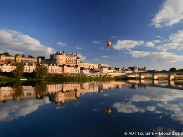 Montgolfière survolant le Château d’Amboise au-dessus de la Loire au coucher du soleil.