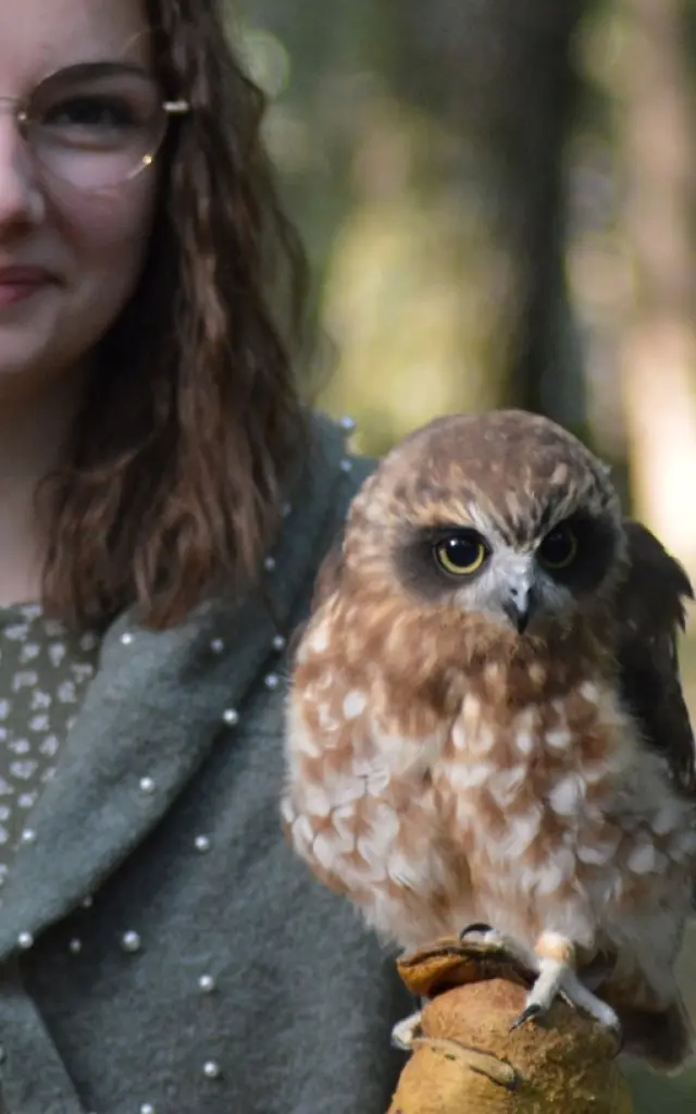 Jeune femme tenant une chouette en forêt lors d’une activité nature en Sud Val de Loire.