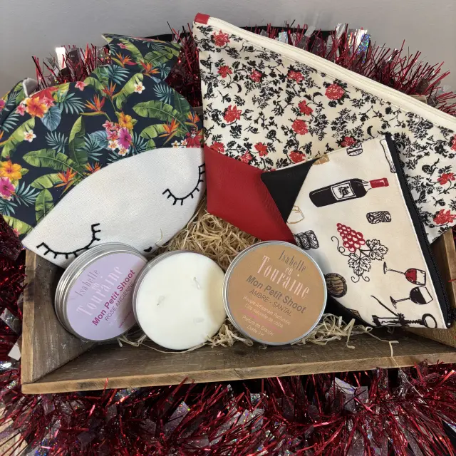 Panier cadeau contenant des trousses en tissu à motifs variés et des bougies artisanales parfumées.