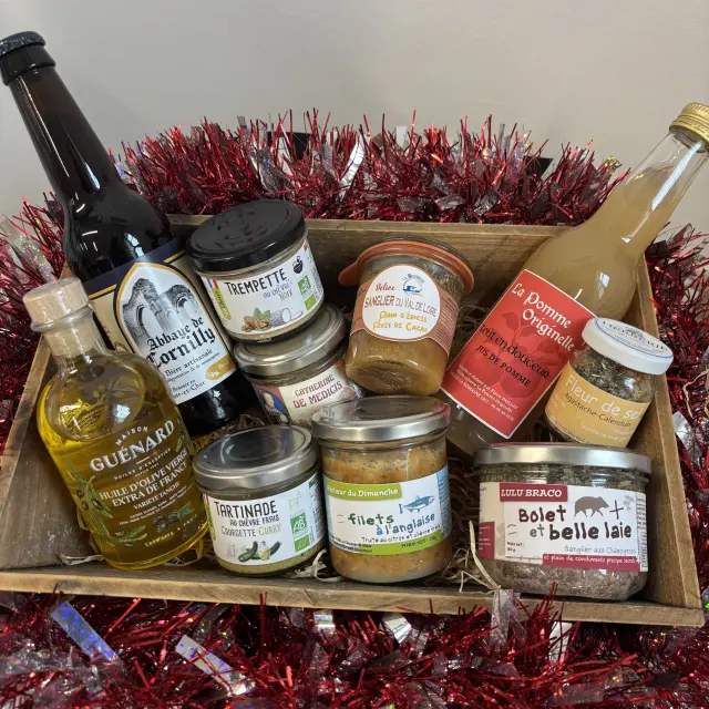 Panier garni composé de produits locaux du Val de Loire, incluant boissons, tartinades, condiments et conserves artisanales, présenté dans une caisse en bois avec décoration rouge pailletée.