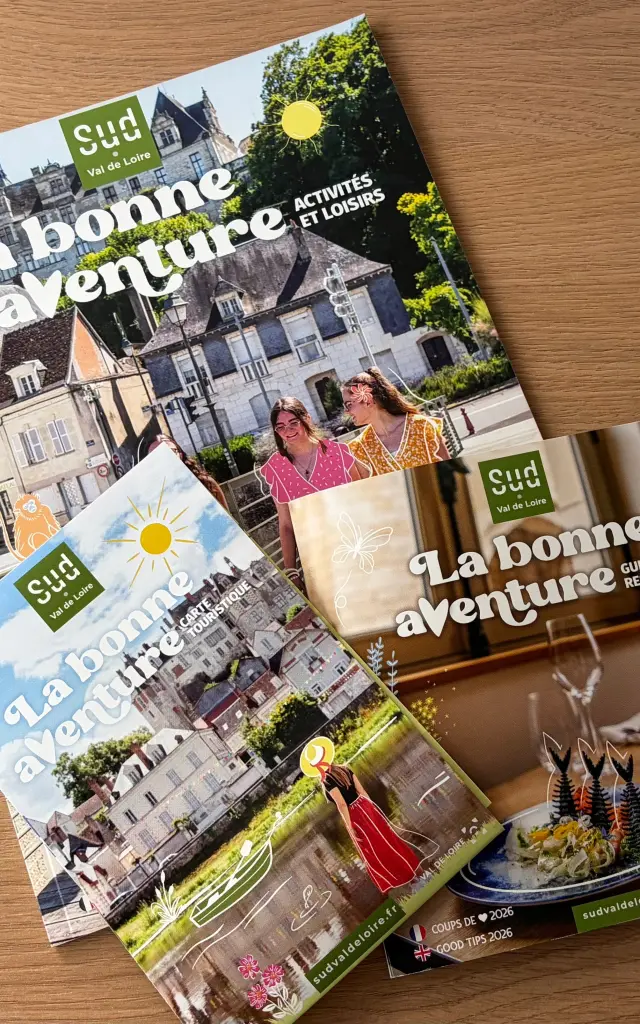 Trois brochures touristiques « Sud Val de Loire » posées sur une table en bois : un guide des activités et loisirs, une carte touristique et un guide des restaurants, tous sont intitulés « La bonne aventure ».