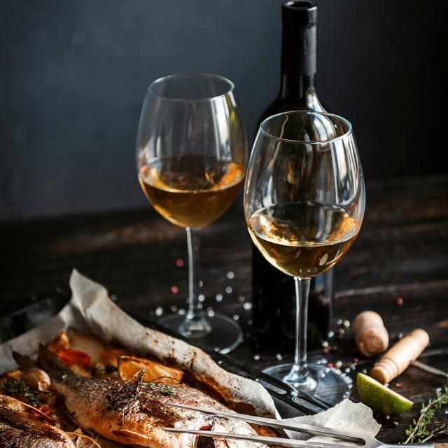 dinner concept for two. two glasses of white wine, baked fish.