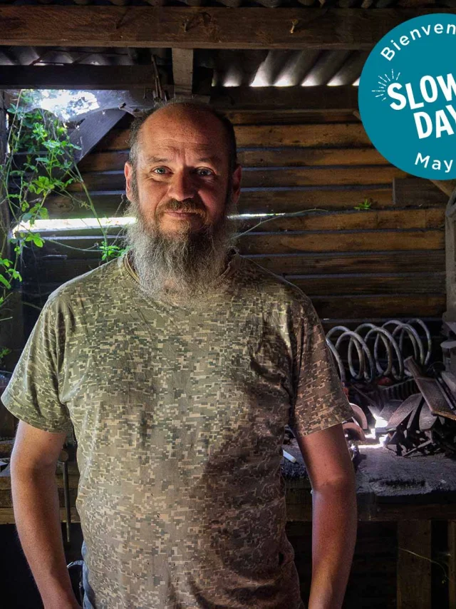 Emmanuel Davoust, coutelier-forgeron à Vaiges, dans son atelier traditionnel entouré de ses outils. En haut à droite de l'image on peut voir l'estampille Slowlydays en blanc sur fond bleu