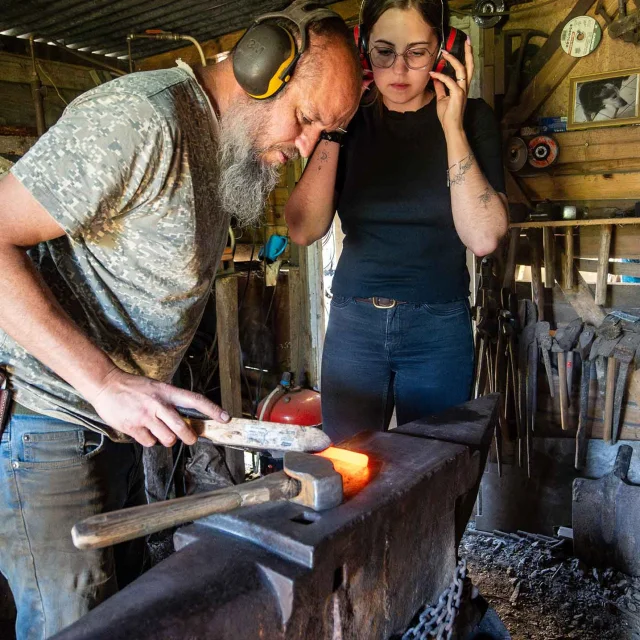 Emmanuel Davoust forge une lame chauffée au rouge devant une stagiaire, dans son atelier à Vaiges.