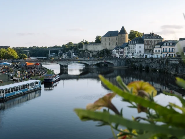 La ville de Mayenne, douce lumière de fin de journée. Vue sur le château, la rivière et le bateau La Meduana.