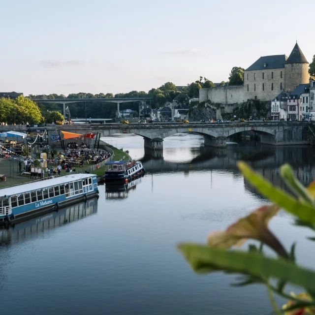La ville de Mayenne, douce lumière de fin de journée. Vue sur le château, la rivière et le bateau La Meduana.