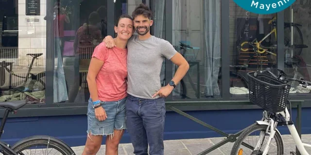 Marine et Damien posent souriants devant leur établissement Tartine & Rustine à Laval. Ils sont , entourés de vélos. Un badge Bienvenue SlowlyDays Mayenne apparaît en haut à droite de l'image.