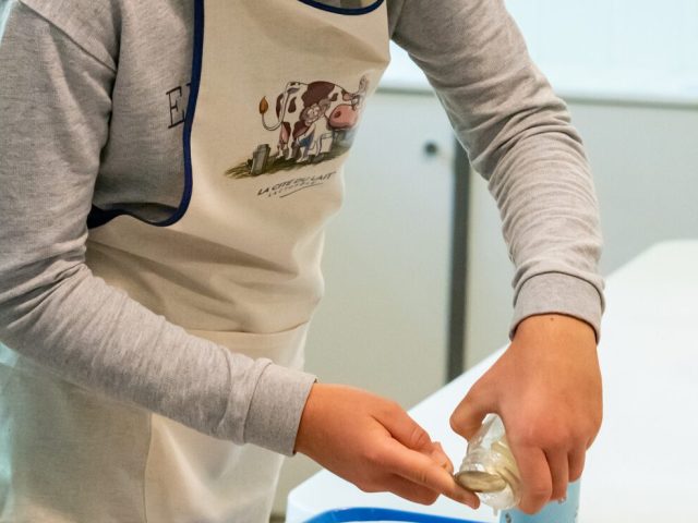 Un jeune garçon en tablier de cuisine prépare des ingrédients dans un atelier culinaire.