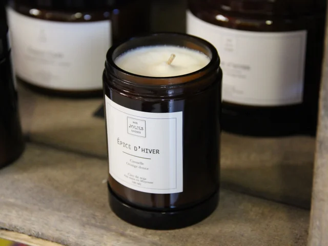 Bougie parfumée 'Épice d'Hiver' en pot en verre brun, étiquetée et non allumée.