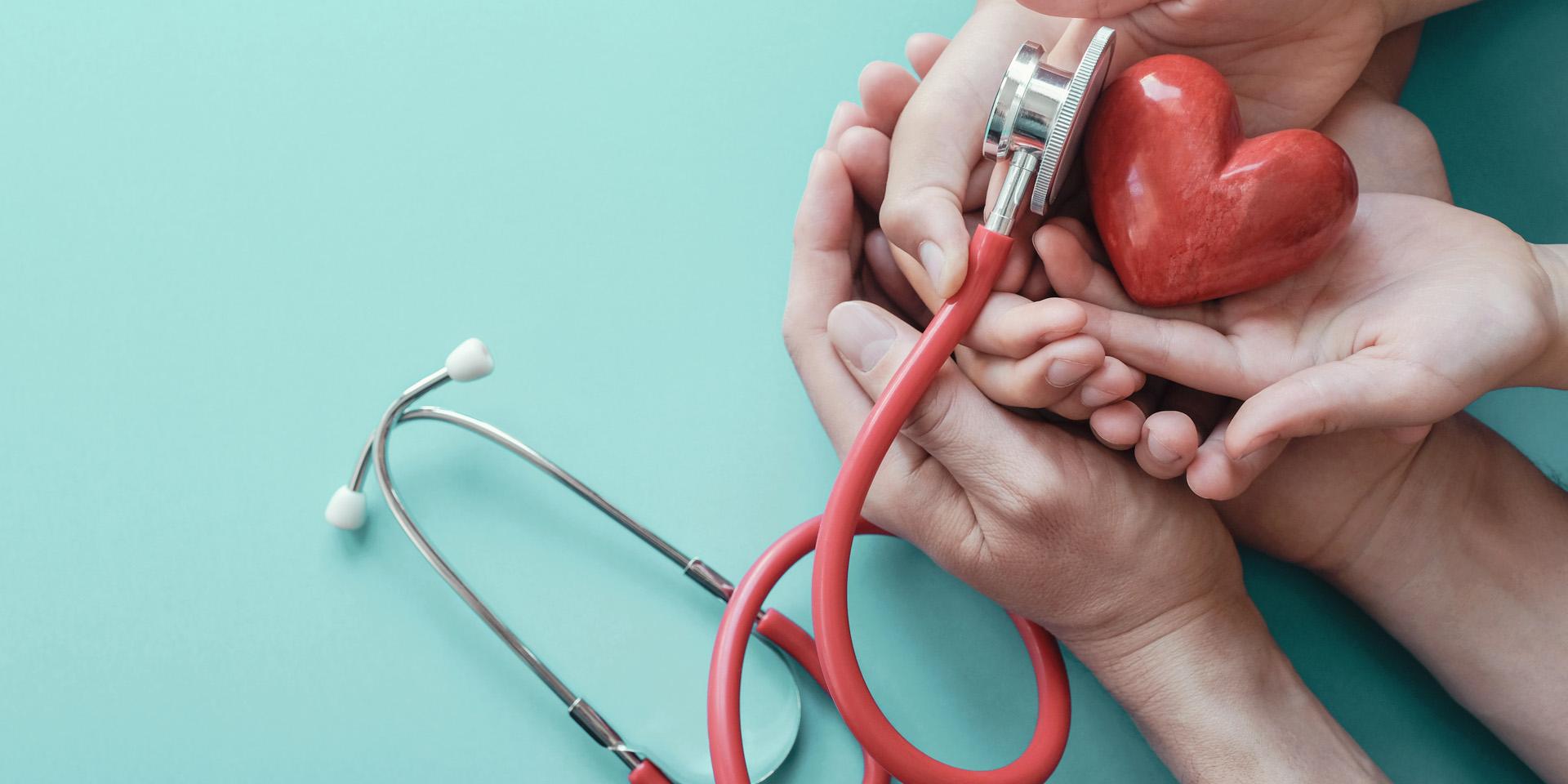 Family hands holding red heart with stethoscope, heart health, health insurance concept, World heart day, world health day