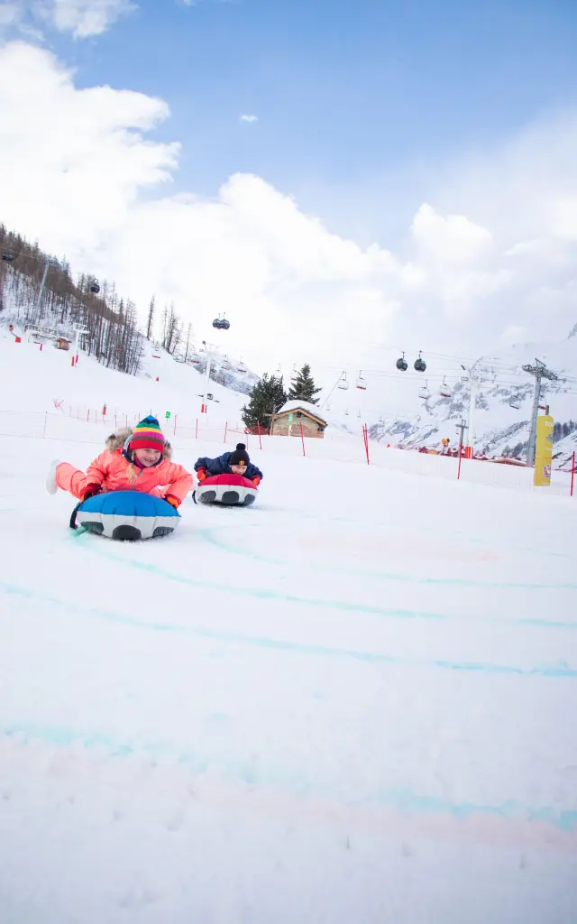 Deux enfants sur le front de neige en train de faire du curling humain à Val d'Isère