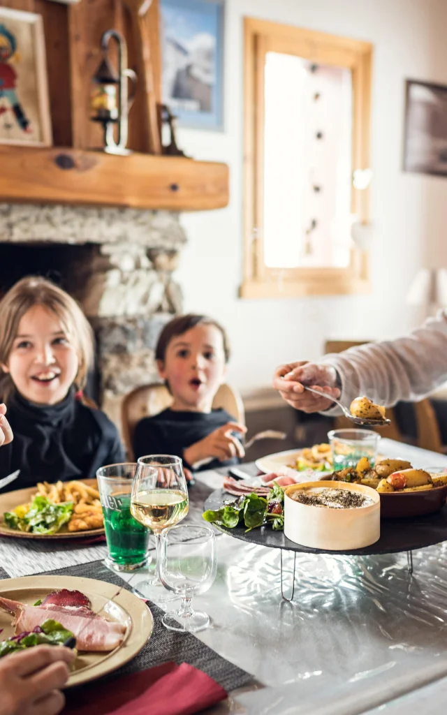 Famiglia con bambini a tavola nel ristorante Au Bout du Monde nella valle di Manchet in Val d'Isère