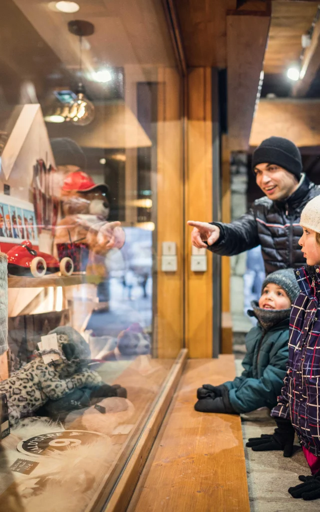 Famille et enfants devant les vitrines des boutiques village à Val d'Isère