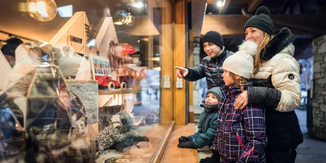 Famille et enfants devant les vitrines des boutiques village à Val d'Isère