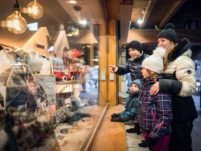 Famille et enfants devant les vitrines des boutiques village à Val d'Isère