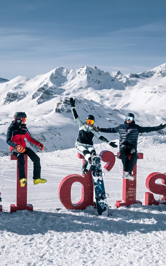 Skiers and snowboarders in front of the Val d'Isère letters