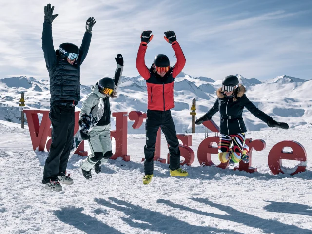 Skiers and snowboarders in front of the Val d'Isère letters