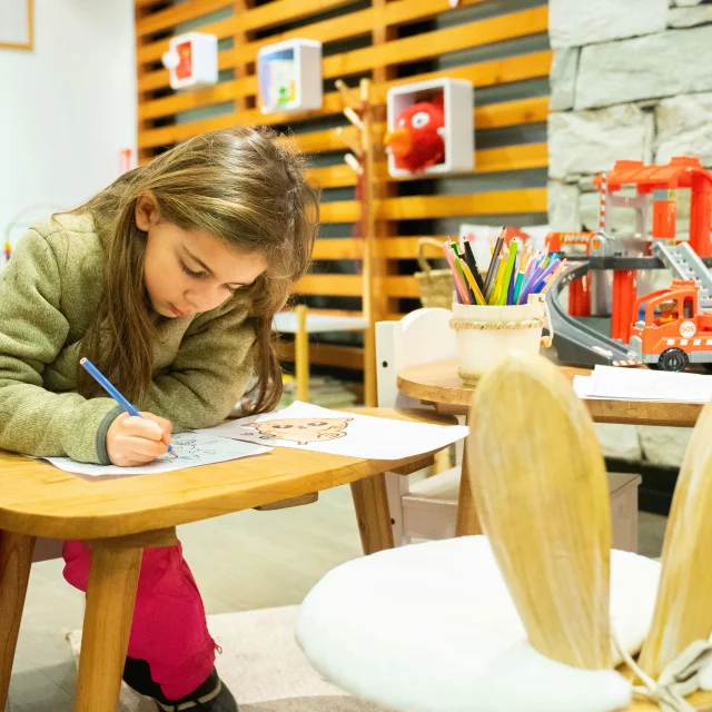 Enfant en train de dessiner avec des crayons de couleurs dans l'espace enfant de l'Office de Tourisme de Val d'Isère