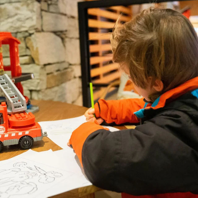 Enfant en train de dessiner dans l'espace enfant de l'Office de Tourisme de Val d'Isère