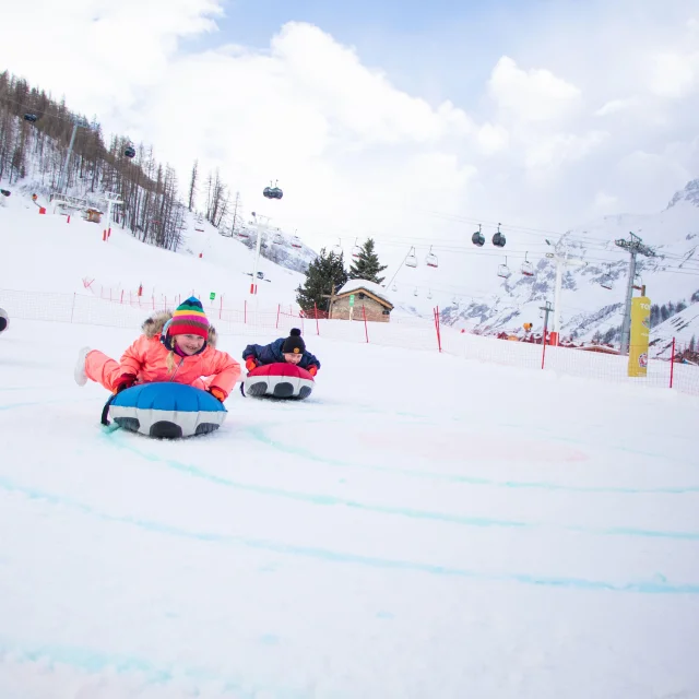 Deux enfants sur le front de neige en train de faire du curling humain à Val d'Isère