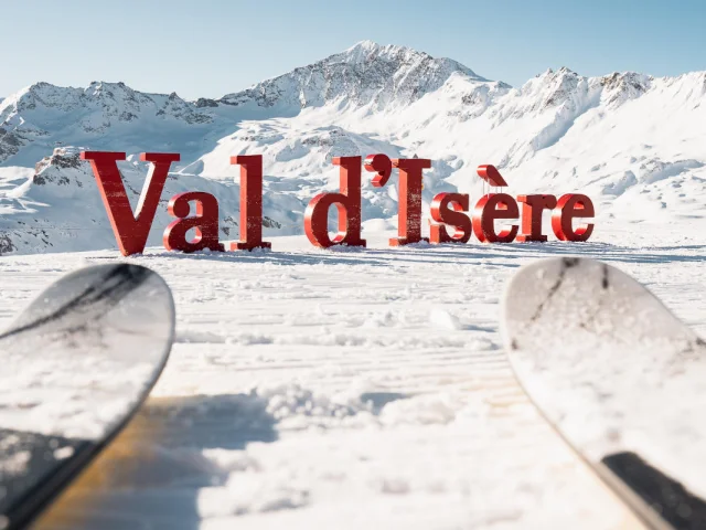 Skiing in front of the giant letters of Val d'Isère in winter under the sun