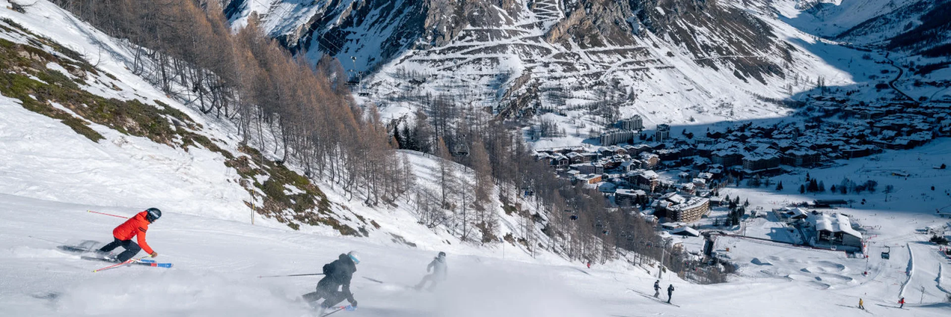 Skieurs dévalant la mythique Face de Bellevarde avec vue sur le village de Val d'Isère