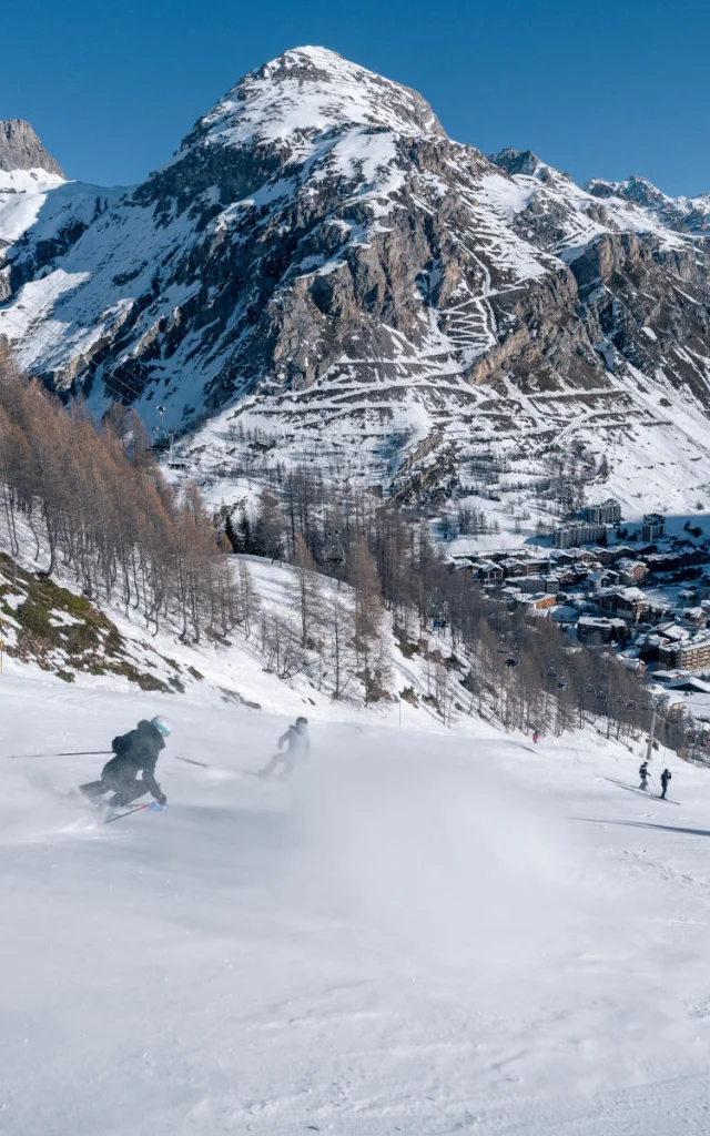 Skieurs dévalant la mythique Face de Bellevarde avec vue sur le village de Val d'Isère