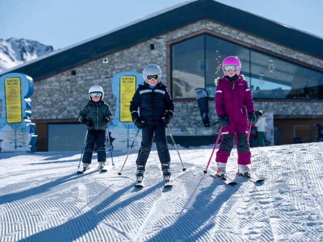 Enfants en ski dans l'espace ludique Val Kids devant une dameuse à Solaise à Val d'Isère