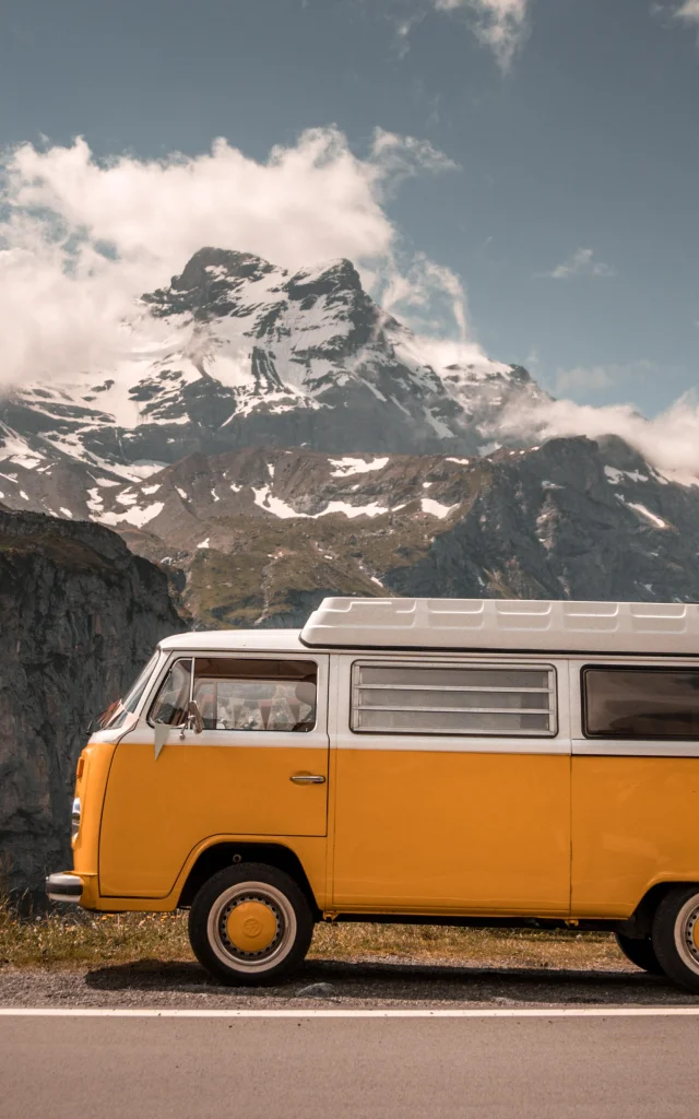 Van ancien sur la route avec montagnes en arrière plan