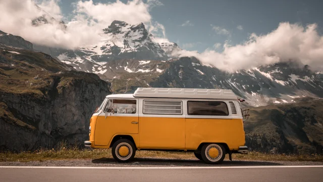 Van ancien sur la route avec montagnes en arrière plan