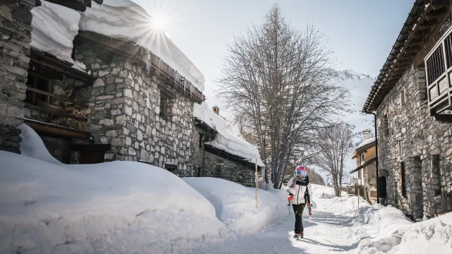 Skieuse qui se déplace dans le village avec ses skis sur l'épaule à Val d'Isère en hiver au Laisinant