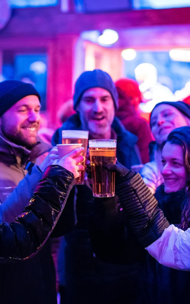 Festive après-ski atmosphere with friends enjoying a drink at the Cocorico bar in winter in Val d'Isère.