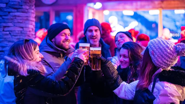 Festive après-ski atmosphere with friends enjoying a drink at the Cocorico bar in winter in Val d'Isère.