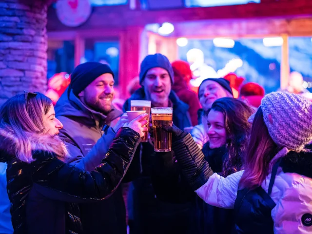 Ambiance festive après-ski entre amis qui prennent un verre dans le bar du Cocorico en hiver à Val d'Isère