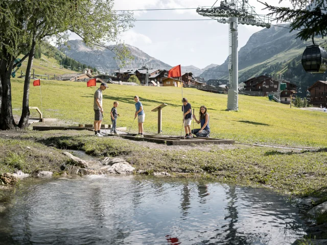 Mini golf en famille (parents et enfant) sur le front de verdure en été à Val d'Isère